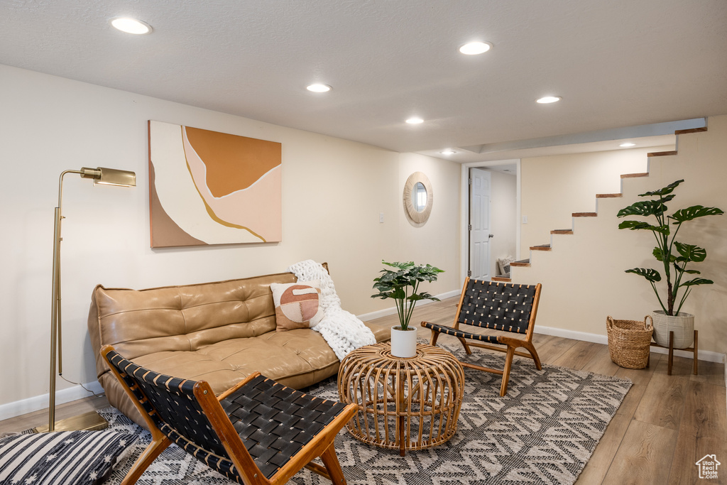 Sitting room with wood finished floors, recessed lighting, and stairway
