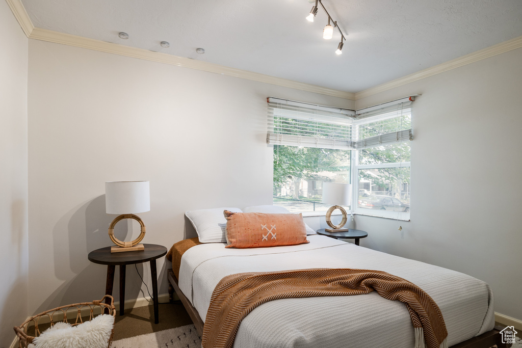 Bedroom featuring crown molding, rail lighting, and carpet