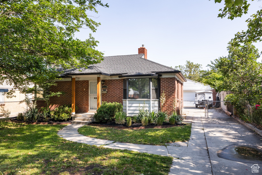 Bungalow-style house with brick siding, a chimney, roof with shingles, and a garage