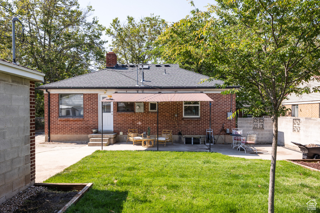 Rear view of property featuring a chimney, a patio, brick siding, and a shingled roof