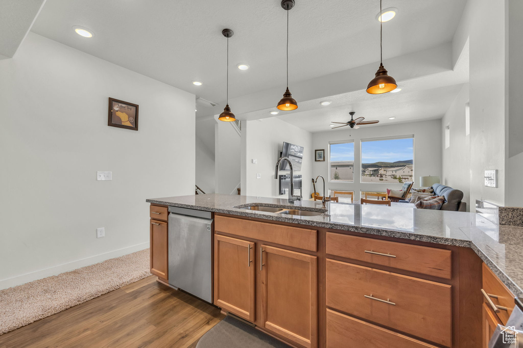 Kitchen with stainless steel dishwasher, brown cabinetry, dark wood-type flooring, open floor plan, and decorative light fixtures