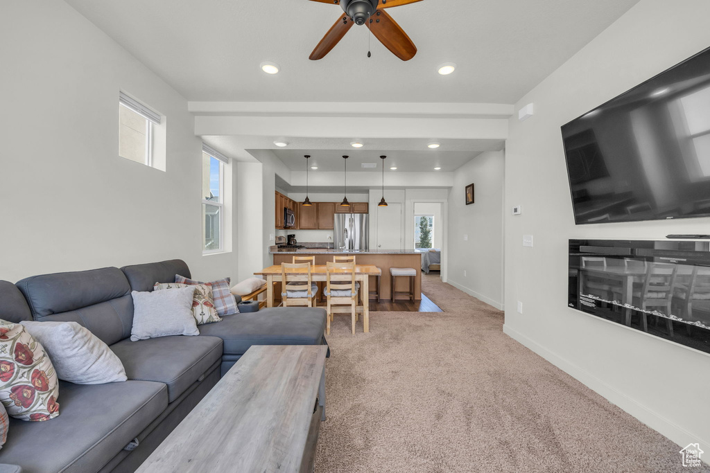 Living area featuring light colored carpet, a ceiling fan, and recessed lighting