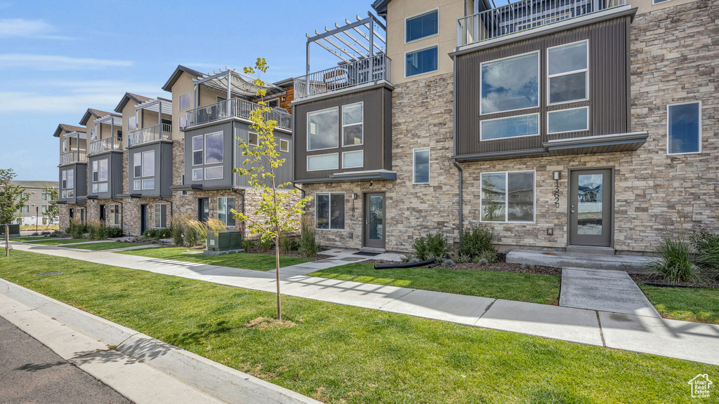 View of front of home featuring a residential view, a front lawn, and a balcony