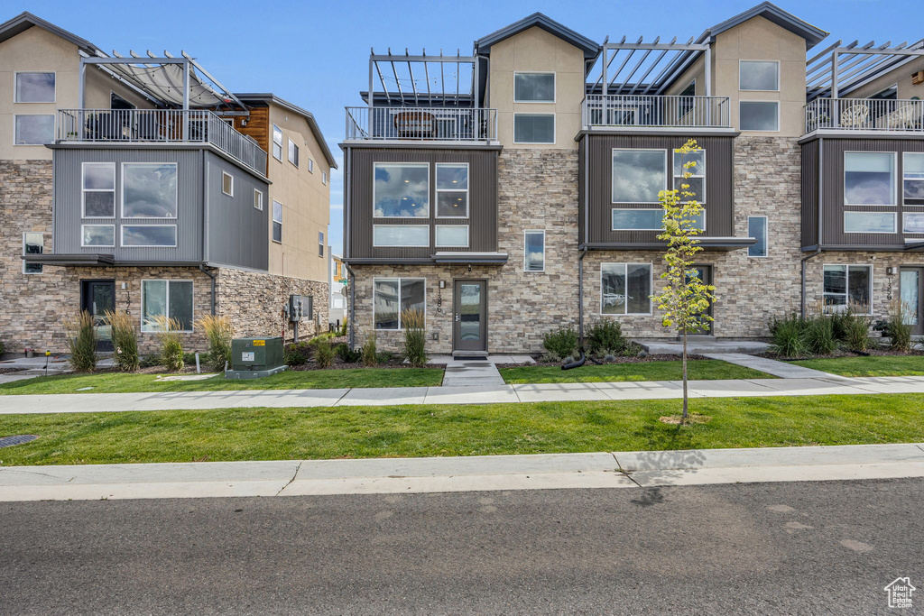 View of property with a balcony and stone siding