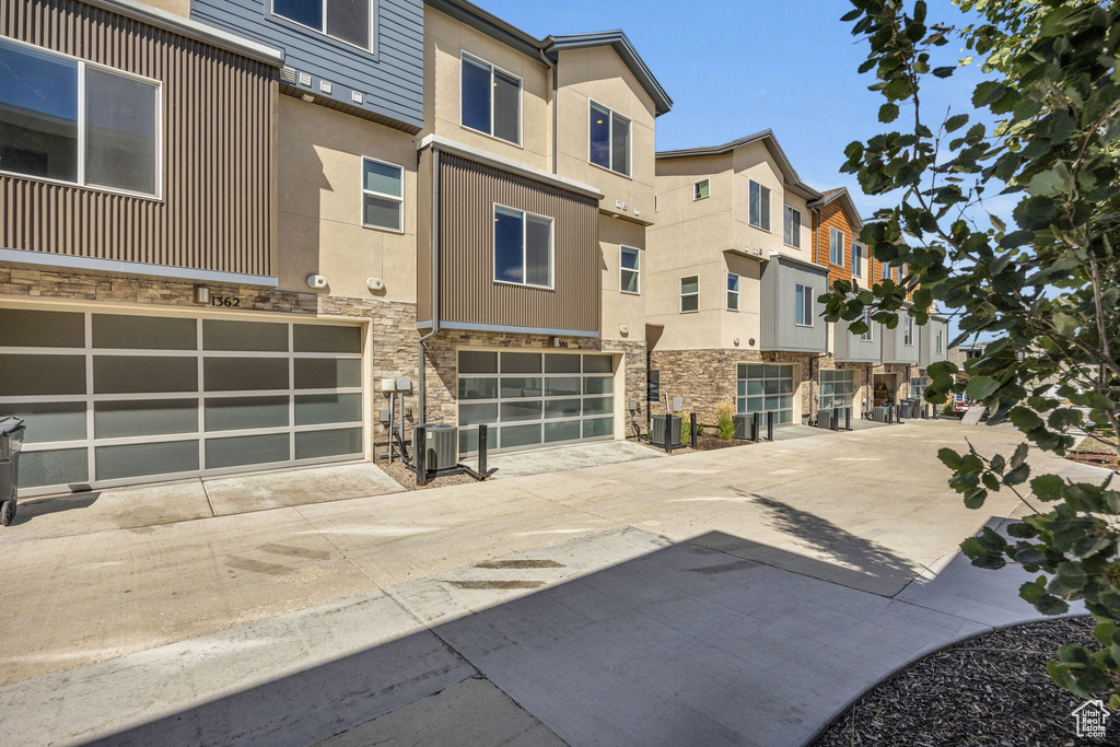 View of building exterior featuring a residential view, driveway, and a garage