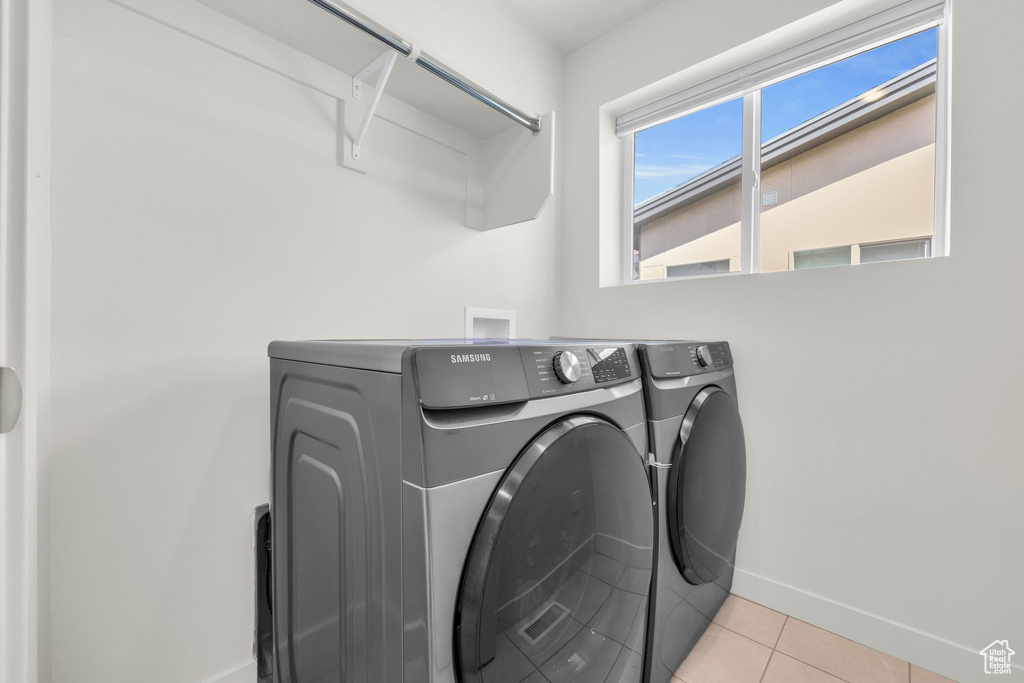 Laundry room featuring washer and clothes dryer and light tile patterned flooring