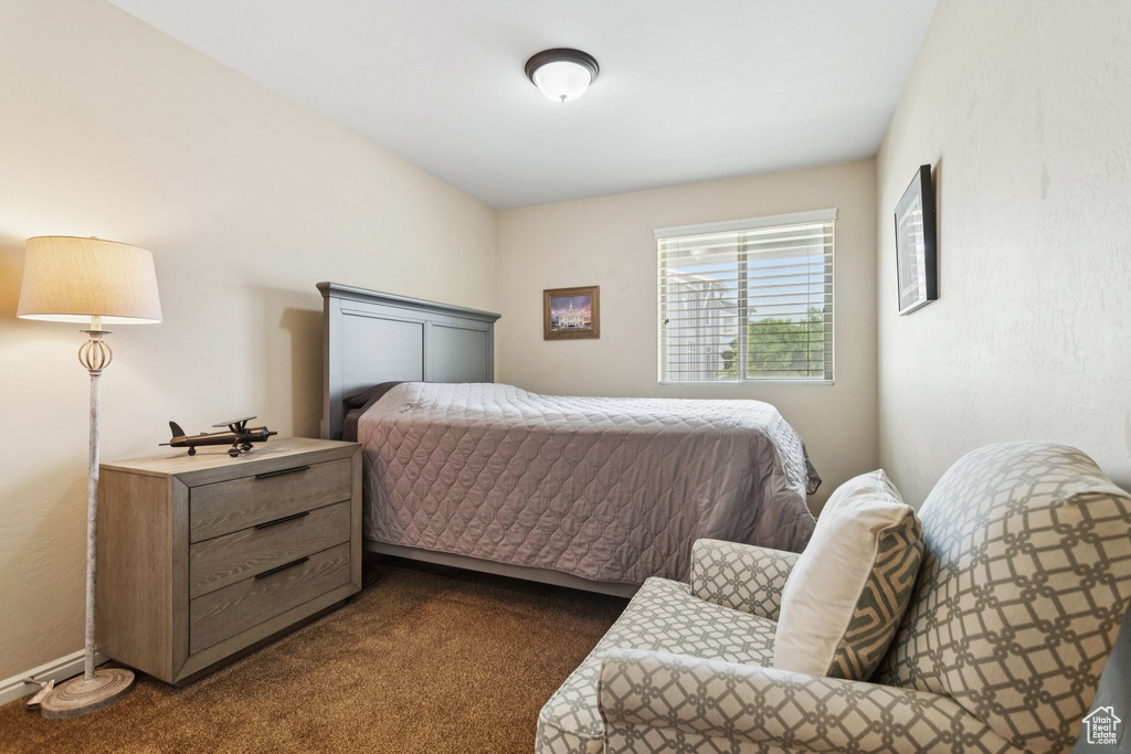 Bedroom with dark colored carpet and baseboards