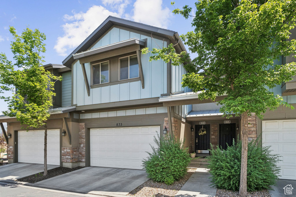 View of front of property featuring stone siding, board and batten siding, a garage, and concrete driveway