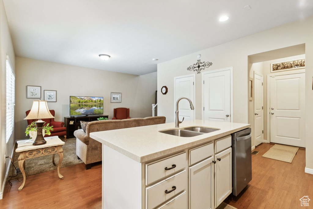 Kitchen with dishwasher, light wood-style flooring, light countertops, an island with sink, and recessed lighting
