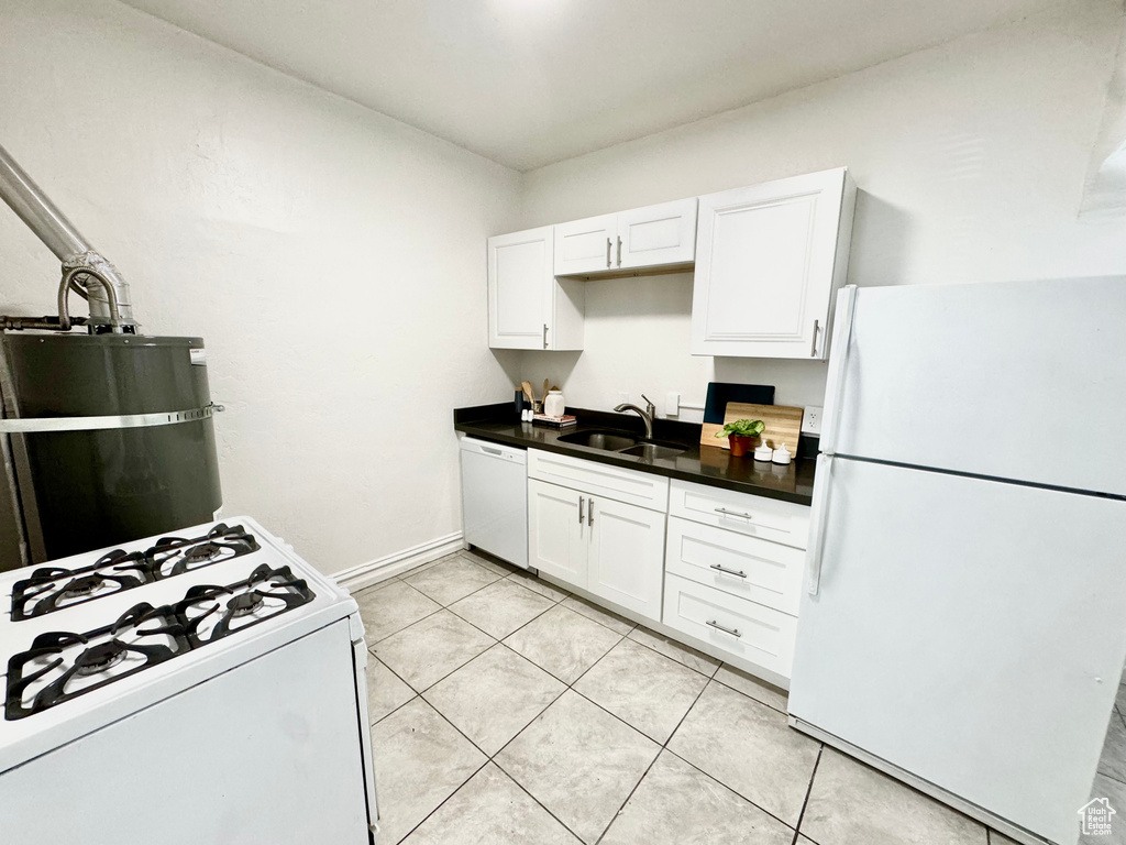 Kitchen with white appliances, white cabinetry, dark countertops, and light tile patterned floors