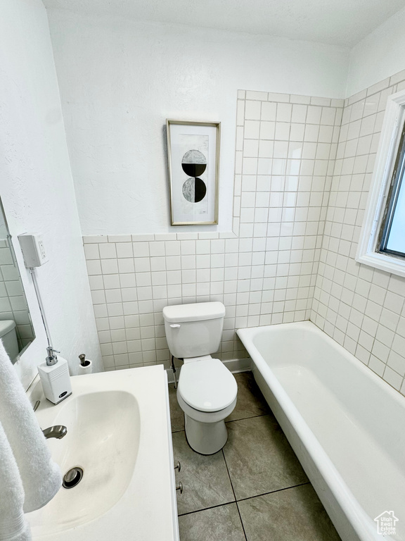 Full bathroom with a tub to relax in, tile patterned flooring, and tile walls