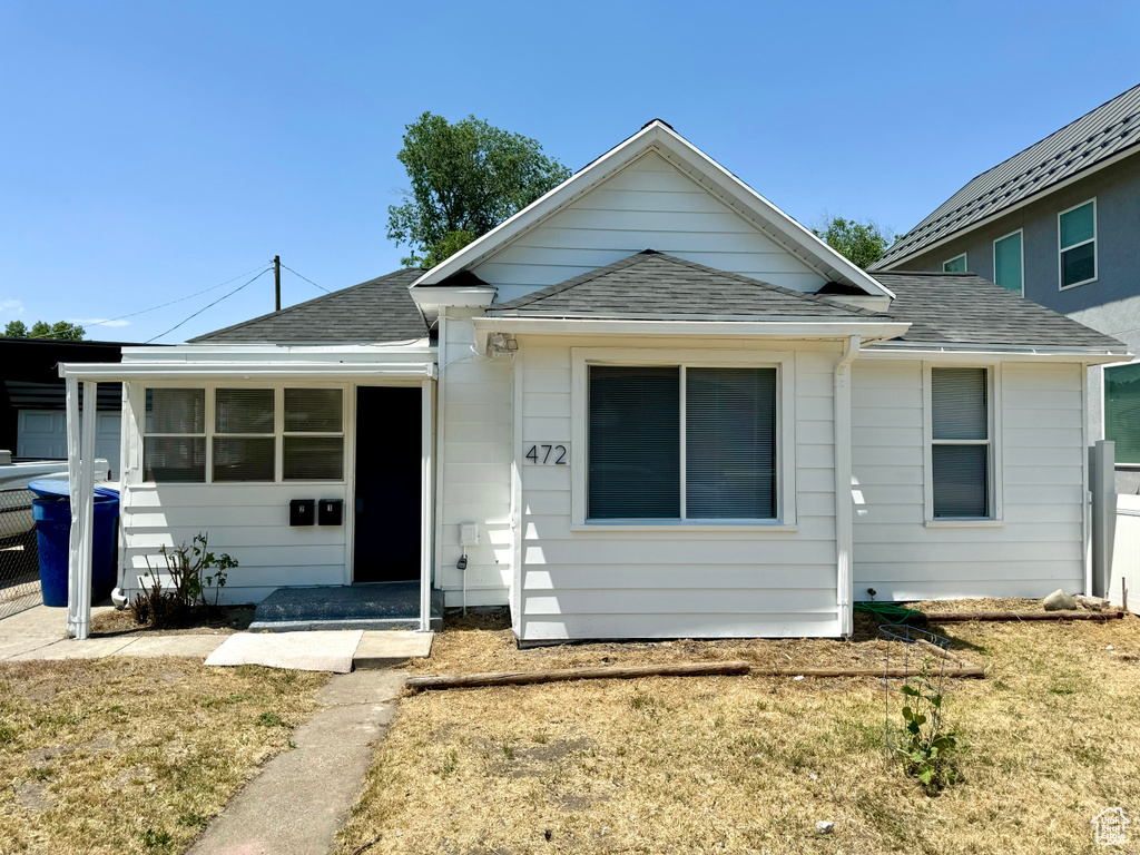 View of front of property with roof with shingles and a front lawn