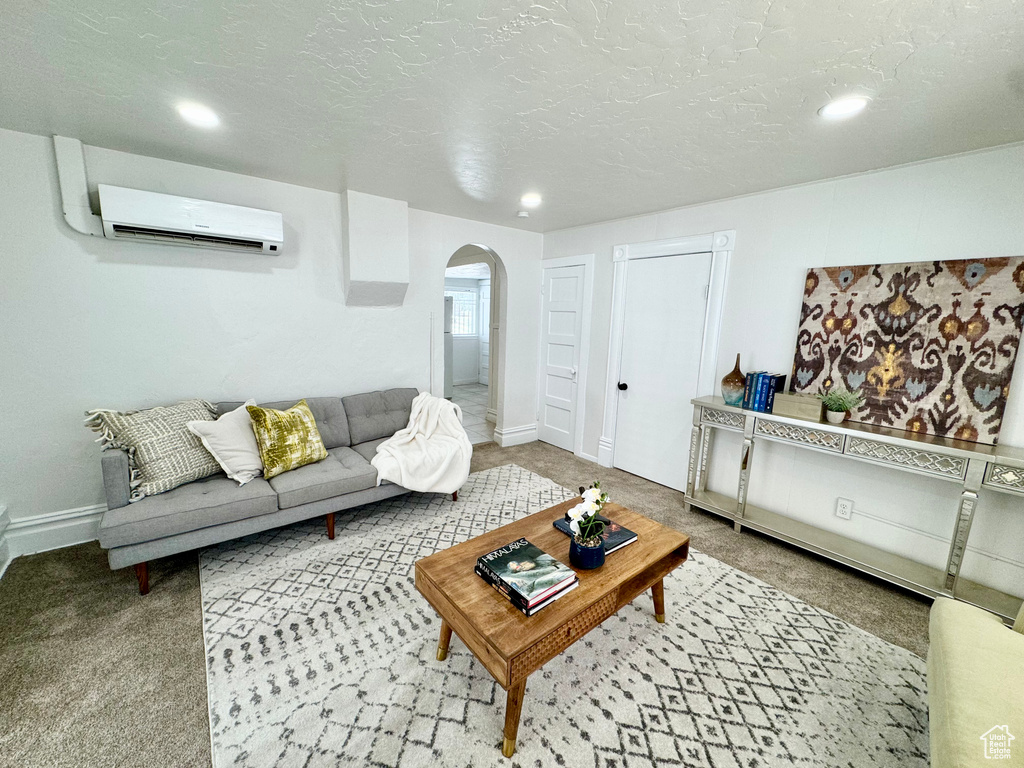 Carpeted living area featuring a wall mounted AC, arched walkways, and recessed lighting