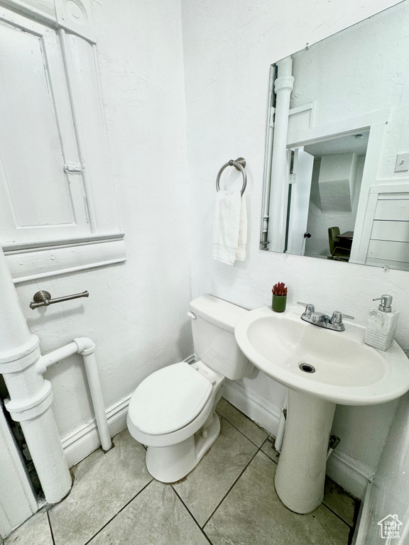 Half bathroom with toilet and tile patterned flooring