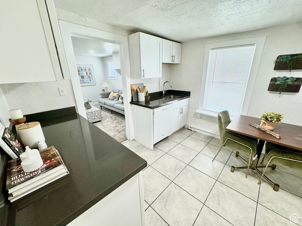 Kitchen featuring white dishwasher, dark countertops, white cabinetry, a textured ceiling, and light tile patterned floors