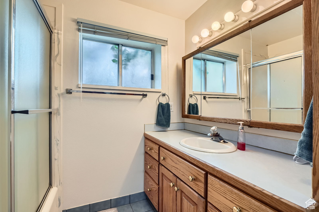Full bathroom with a shower with shower door, vanity, and tile patterned floors