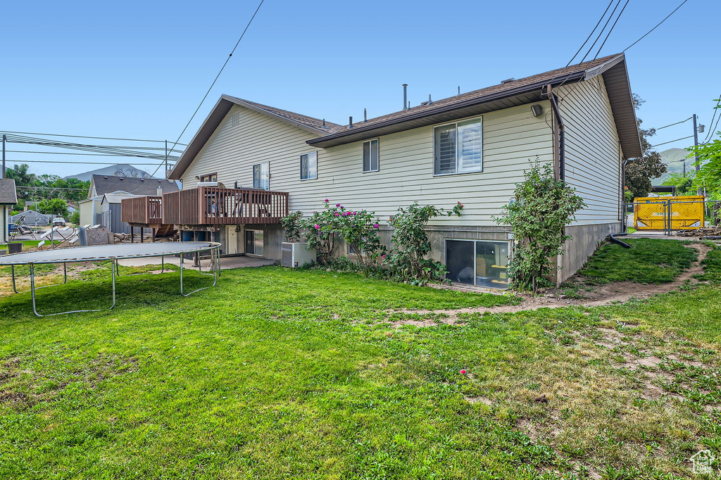 Back of house with a trampoline and a deck