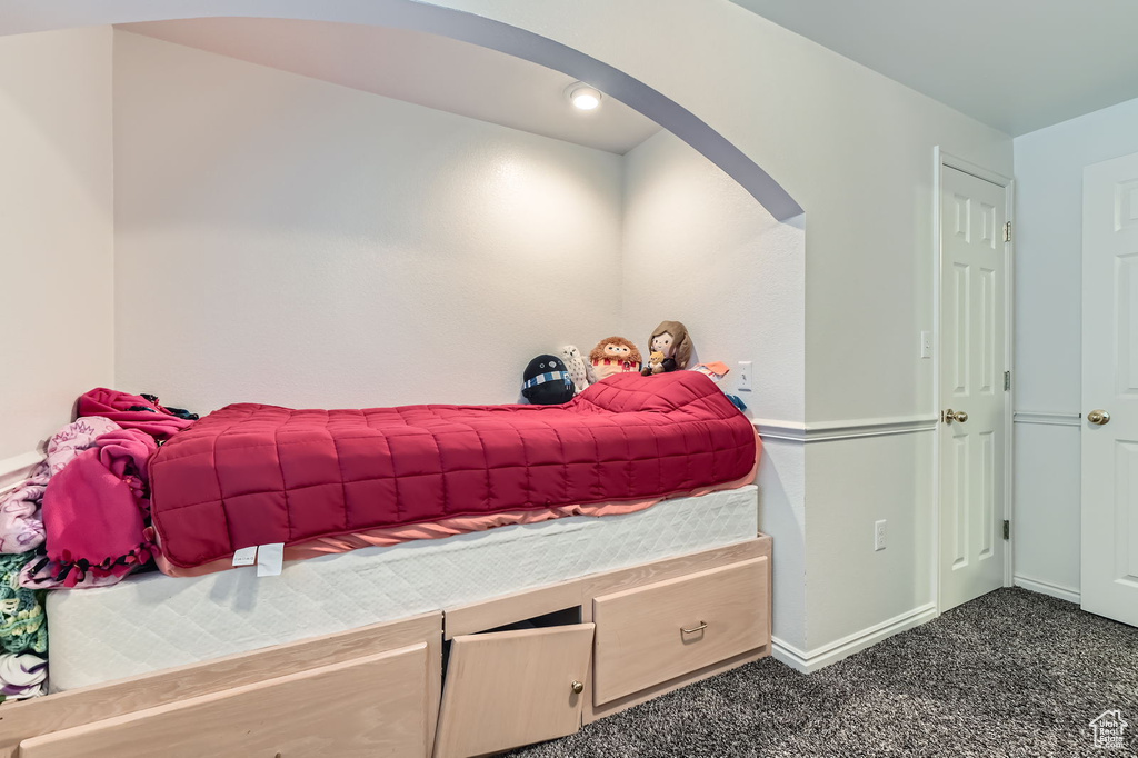 Bedroom featuring arched walkways and dark colored carpet