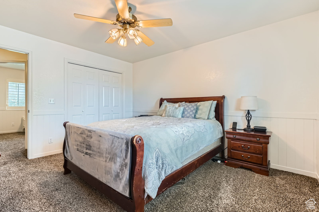 Bedroom with carpet floors, a wainscoted wall, a closet, and ceiling fan
