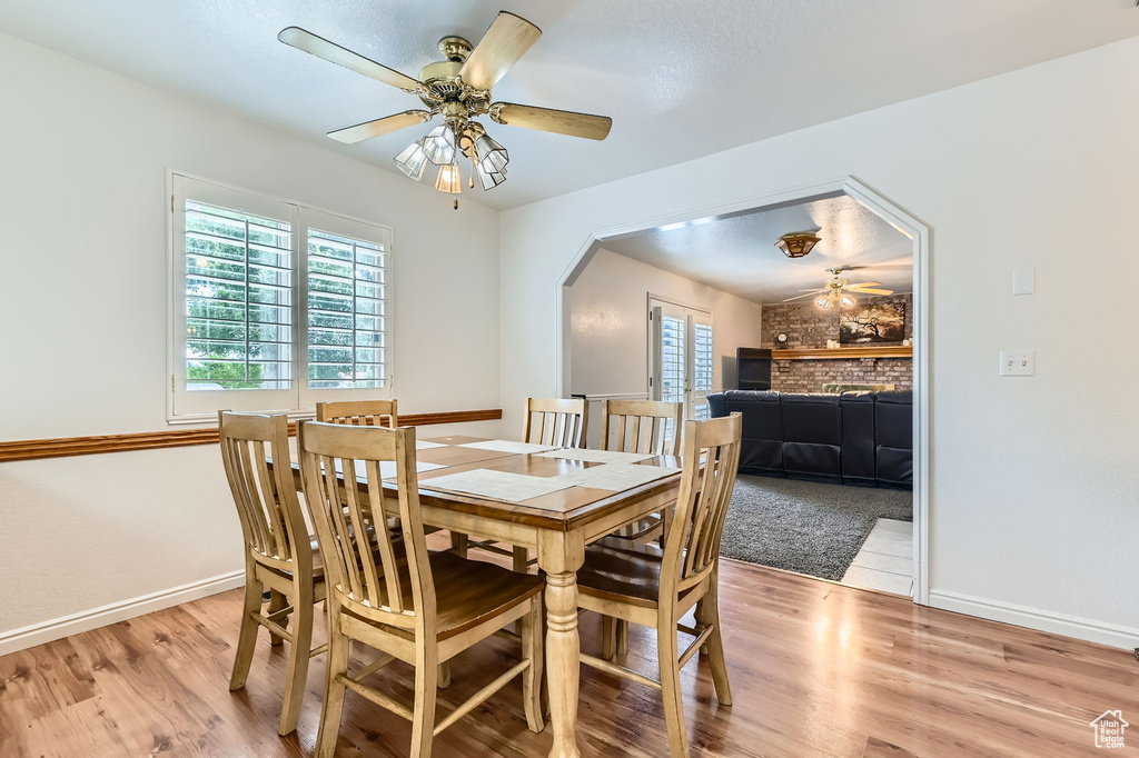 Dining area with a ceiling fan, light wood-style flooring, and arched walkways