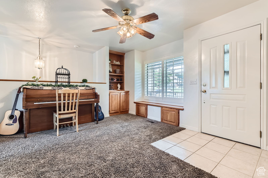 Home office with ceiling fan, light colored carpet, and light tile patterned floors