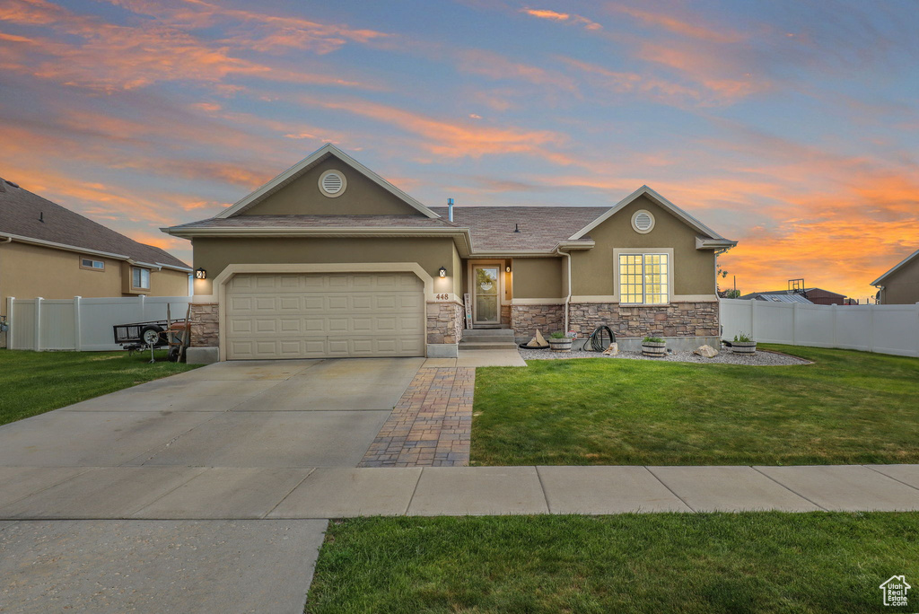 View of front of property with stucco siding, stone siding, concrete driveway, and an attached garage