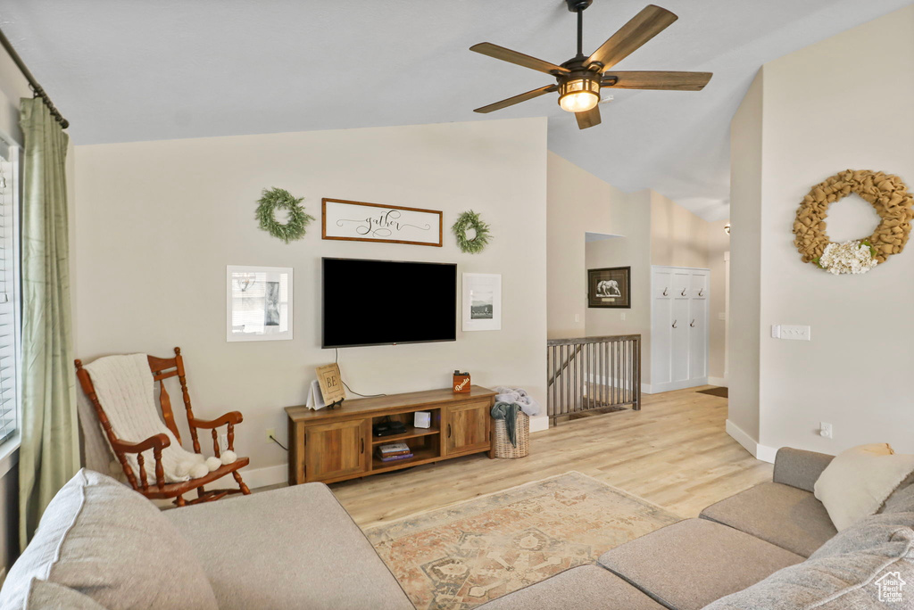Living room with vaulted ceiling, light wood-style floors, and ceiling fan