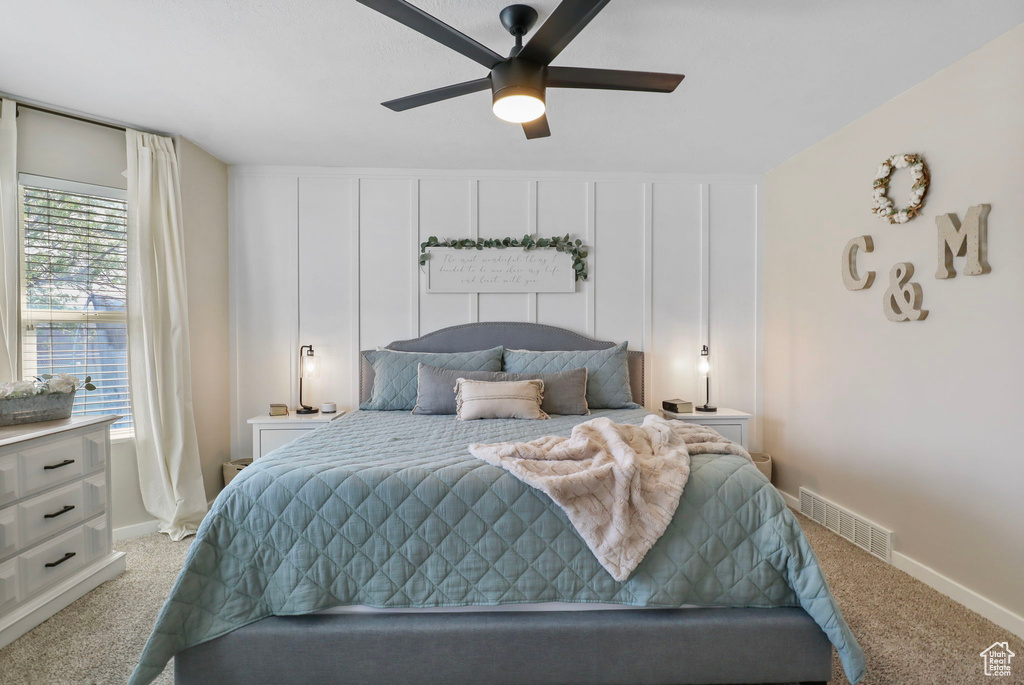 Bedroom with light colored carpet and a ceiling fan