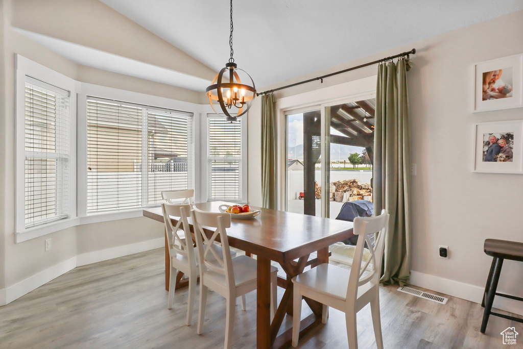 Dining space with a chandelier, vaulted ceiling, light wood-type flooring, and a water view