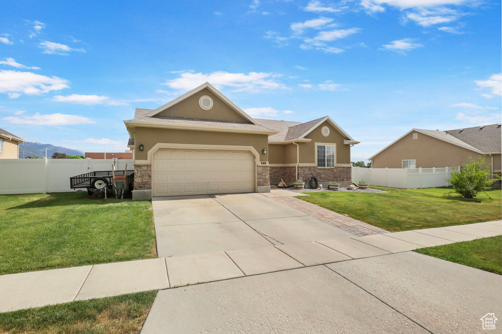 View of front of house featuring stucco siding, stone siding, driveway, and a garage