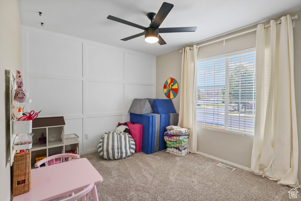 Playroom featuring ceiling fan, carpet floors, and a decorative wall