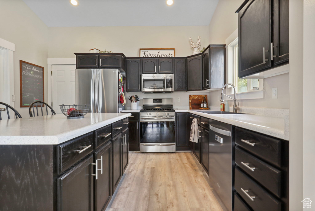 Kitchen featuring appliances with stainless steel finishes, light wood-style floors, light countertops, a kitchen island, and recessed lighting