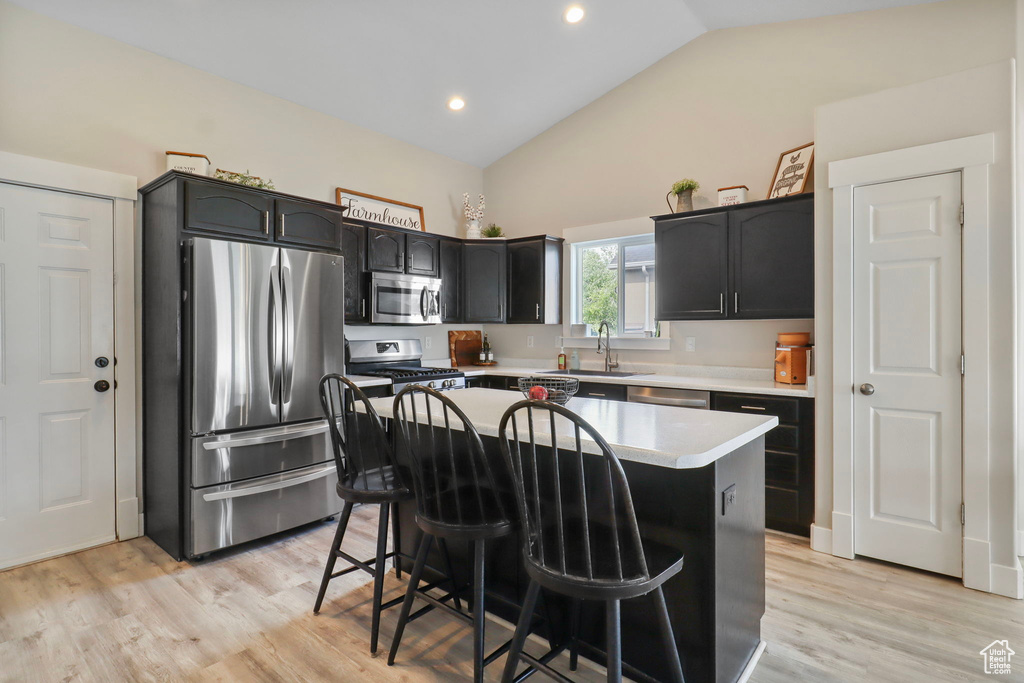 Kitchen featuring stainless steel appliances, a breakfast bar, light countertops, a center island, and light wood-style flooring