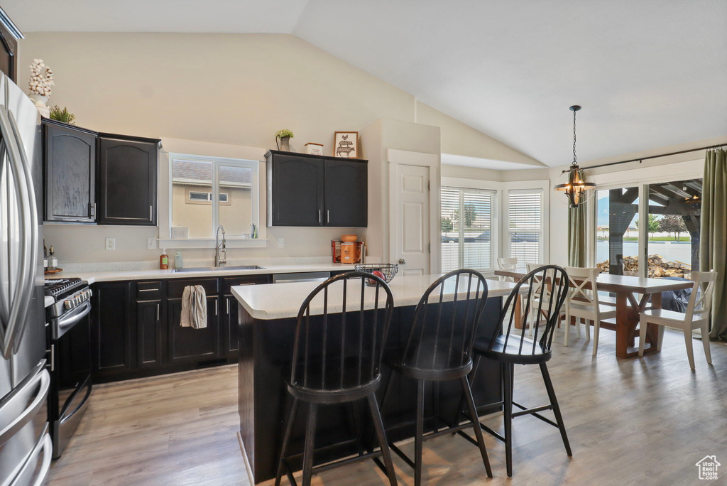 Kitchen with vaulted ceiling, stainless steel appliances, a breakfast bar area, a chandelier, and light countertops
