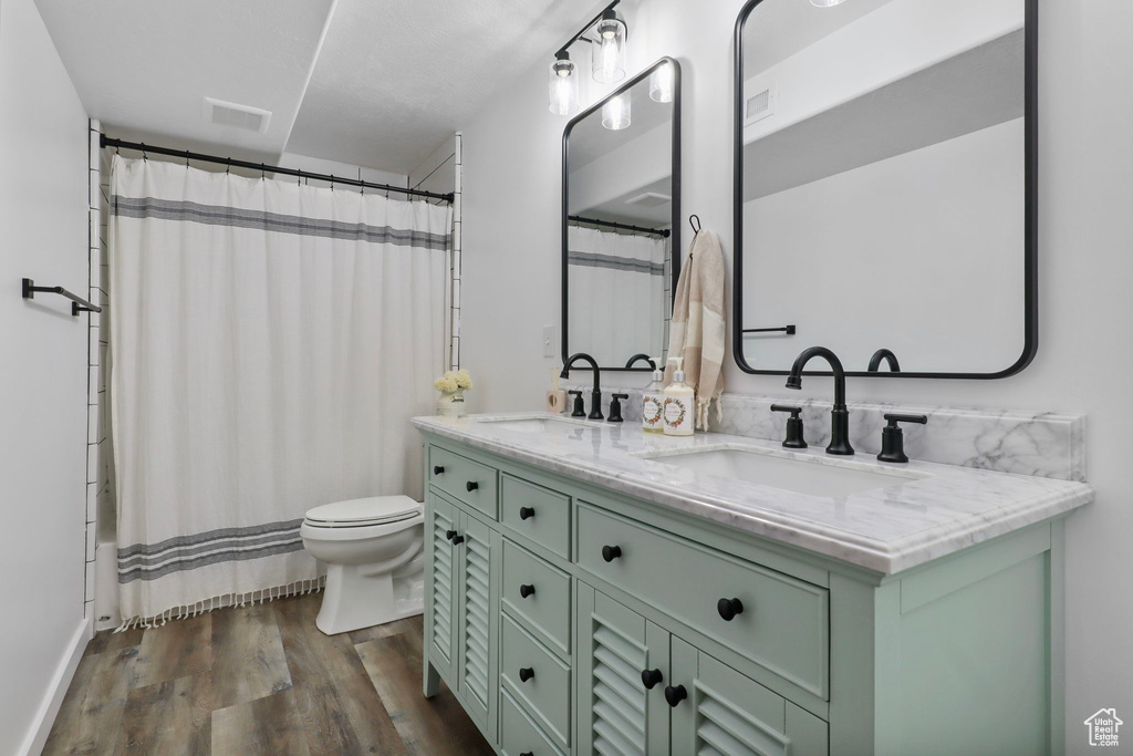 Full bath with double vanity, wood finished floors, and shower / bath combination with curtain