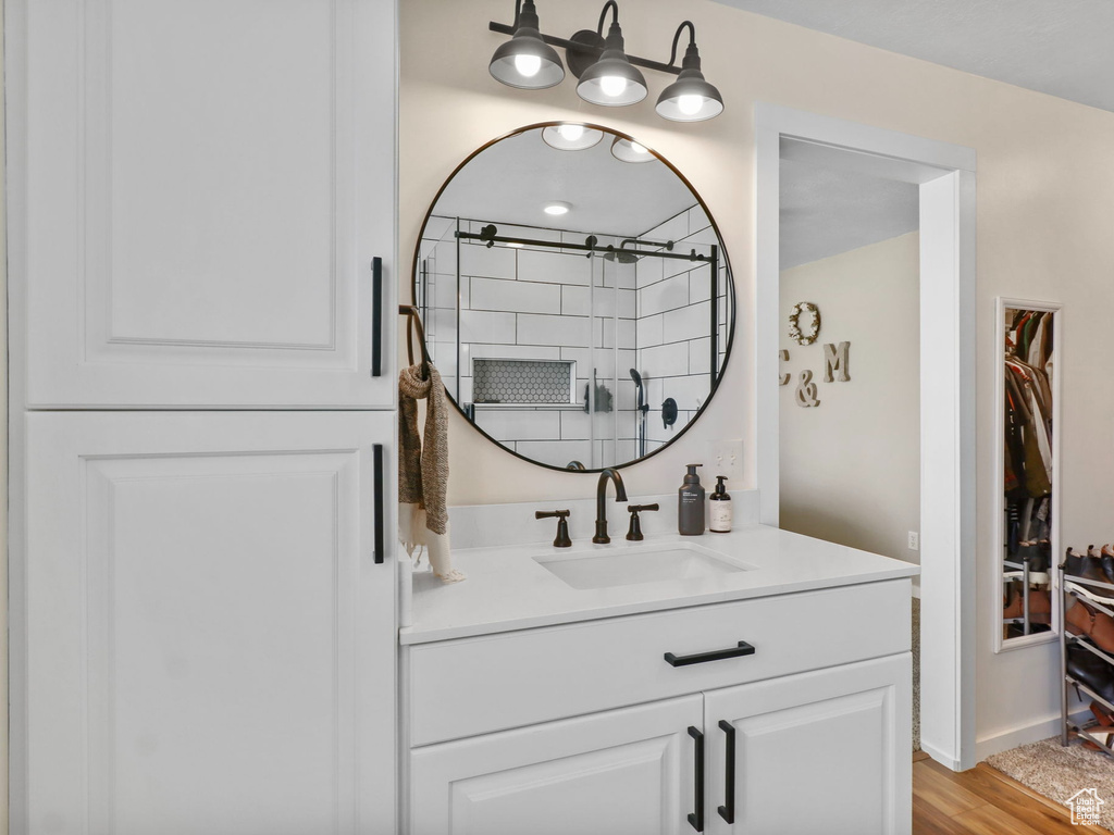 Bathroom with vanity, a shower, and wood finished floors