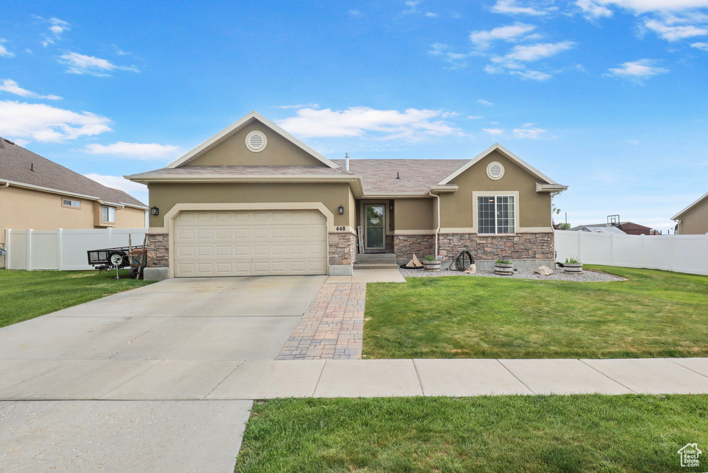 View of front of property with stucco siding, stone siding, a garage, and driveway