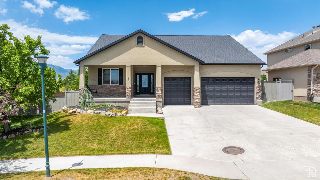 View of front of house featuring a garage, concrete driveway, stucco siding, covered porch, and stone siding