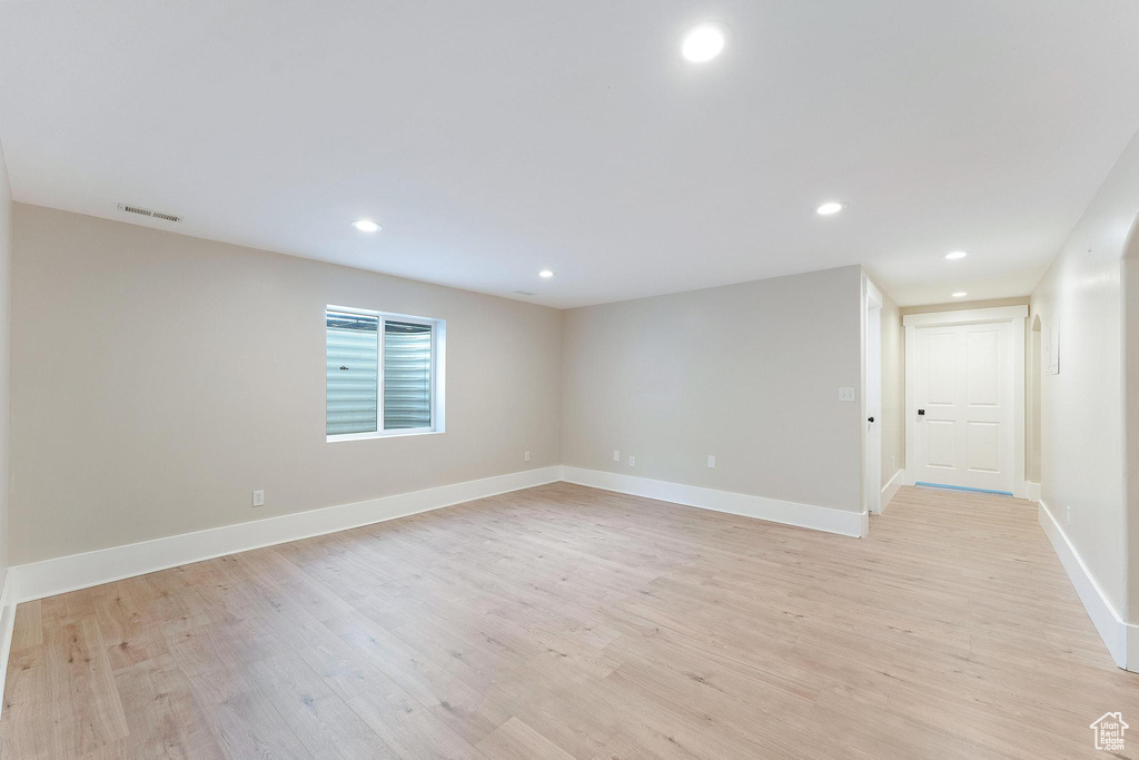 Empty room with light wood-style floors and recessed lighting