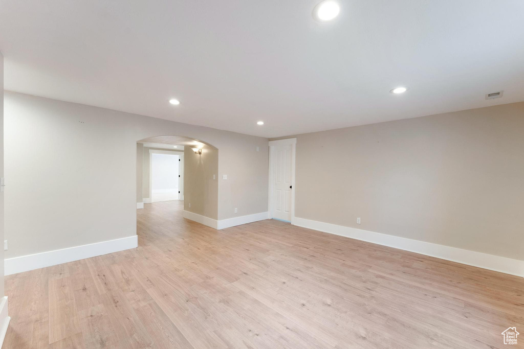 Empty room featuring arched walkways, recessed lighting, and light wood-type flooring