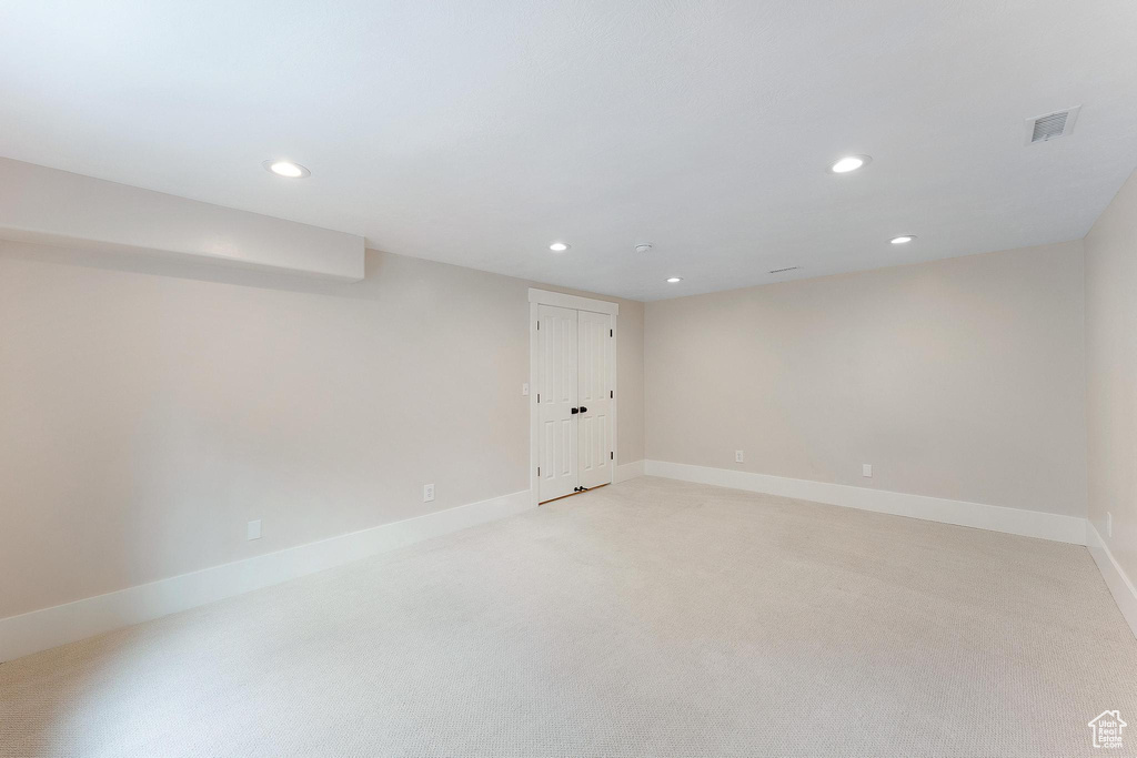 Finished basement with recessed lighting and light carpet