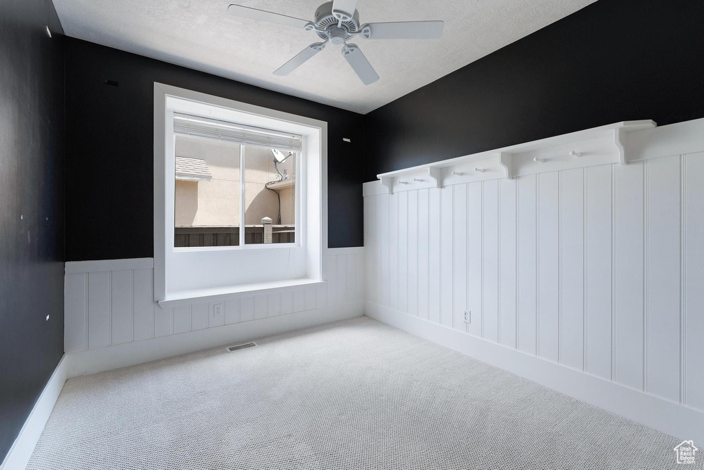 Carpeted empty room with wainscoting and a ceiling fan