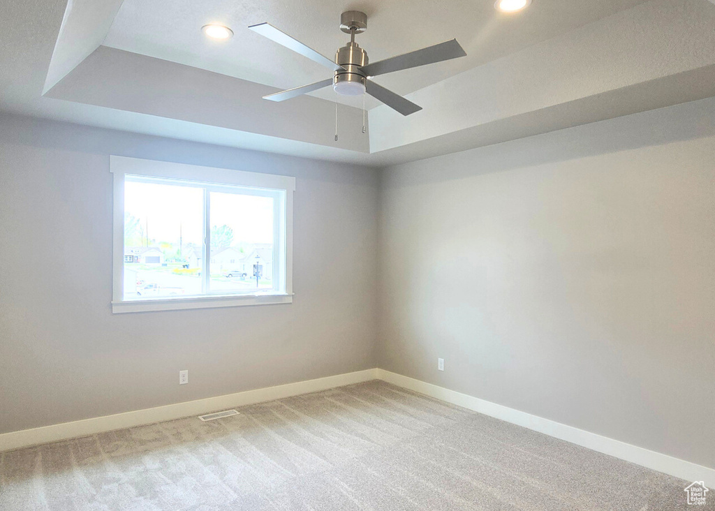 Unfurnished room featuring recessed lighting, a ceiling fan, light carpet, and a tray ceiling