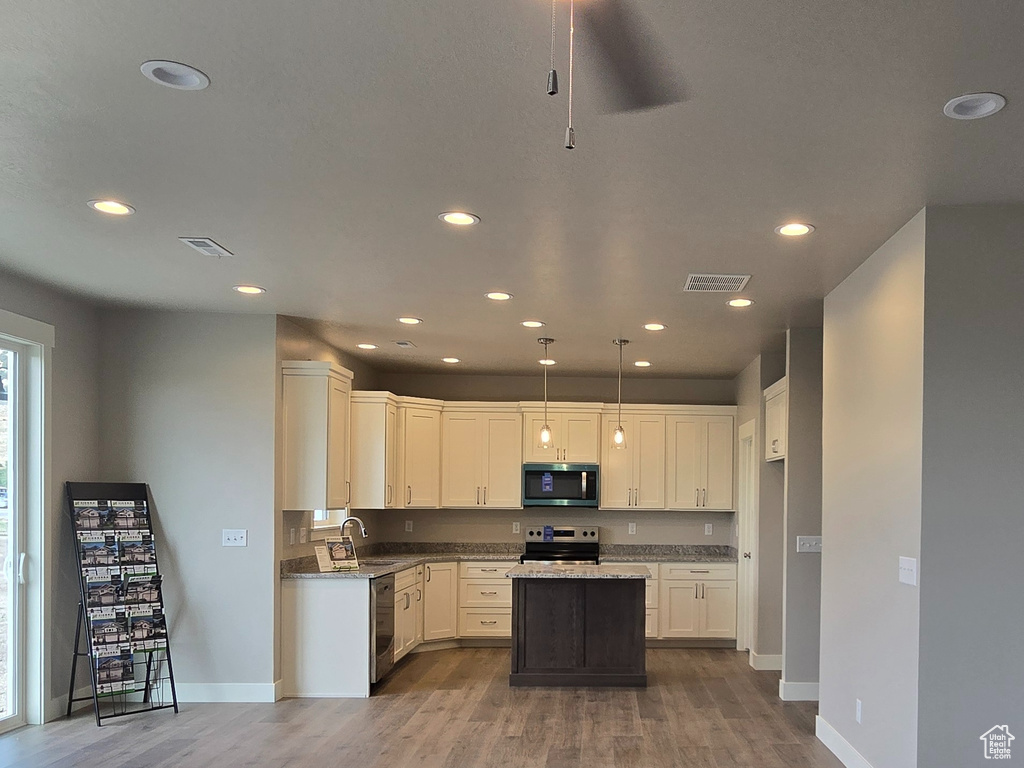 Kitchen featuring stainless steel microwave, range with electric stovetop, light wood finished floors, recessed lighting, and ceiling fan