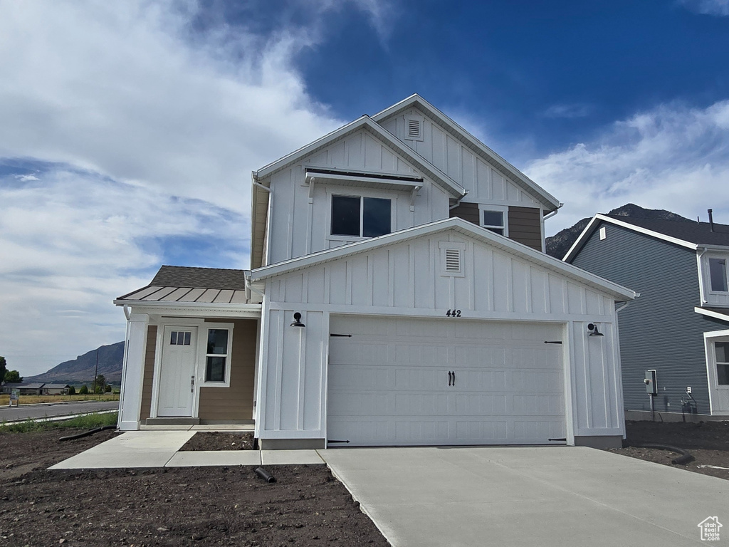 Modern inspired farmhouse featuring board and batten siding, driveway, a garage, and a metal roof