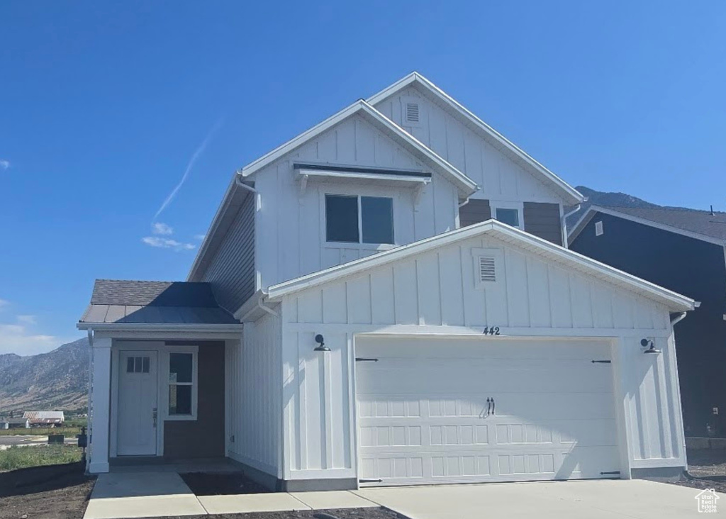 View of front facade with board and batten siding, a mountain view, and driveway