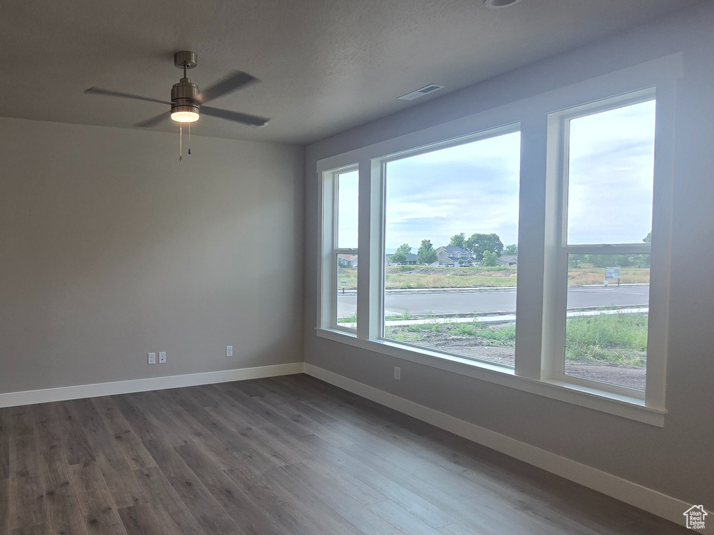 Unfurnished room featuring dark wood-style flooring and ceiling fan