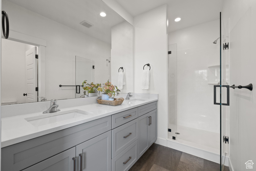 Bathroom with double vanity, a shower stall, and recessed lighting
