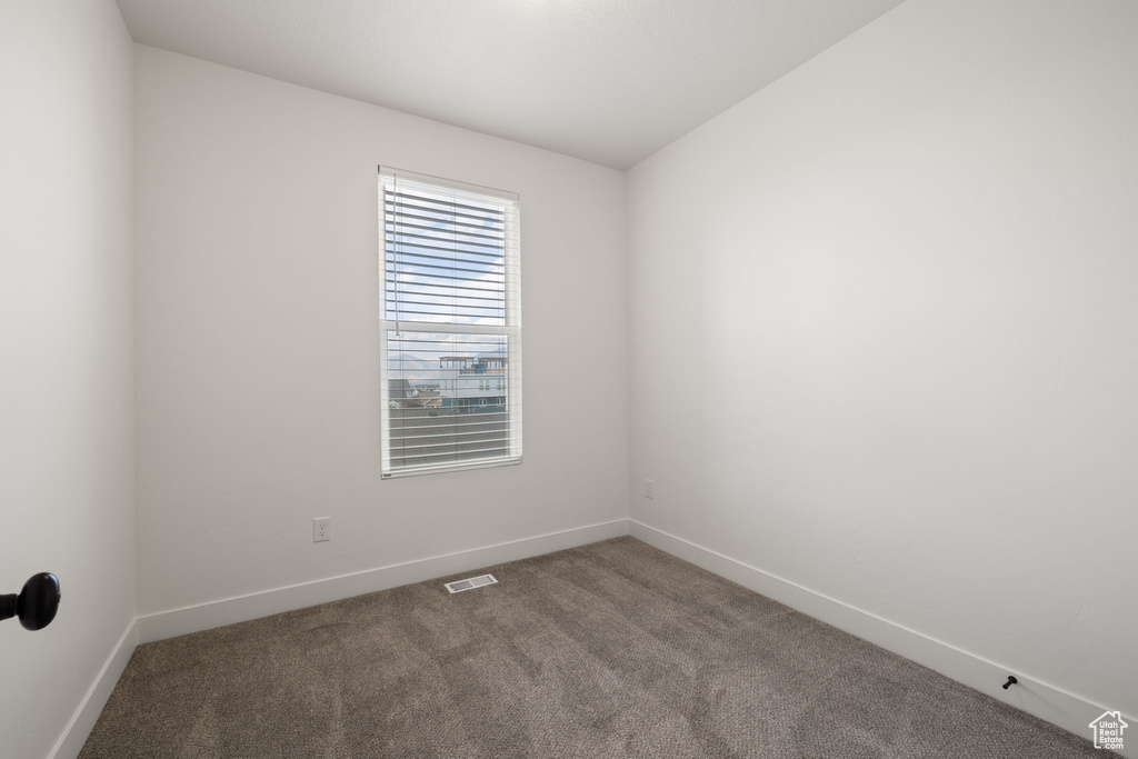 Carpeted spare room featuring baseboards