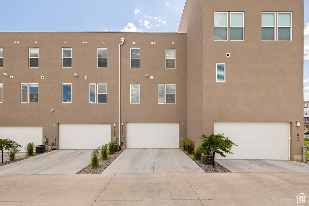 View of building exterior featuring a garage and concrete driveway